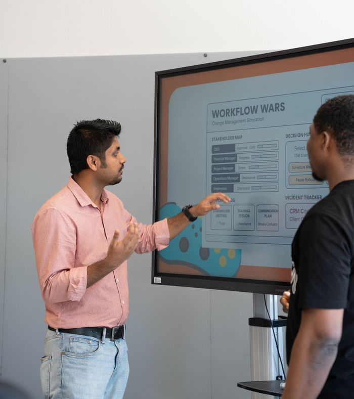 portfolio-05 Two professionals engage in a workflow strategy discussion using a screen display.