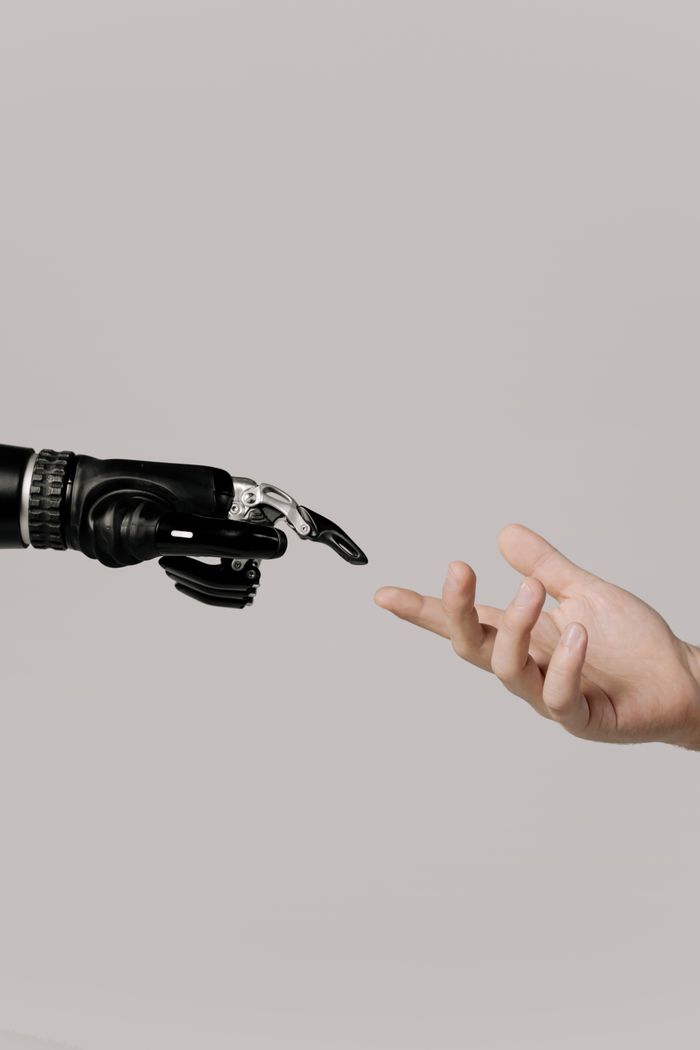 portfolio-01 A human hand reaching to touch a bionic prosthetic hand on a white background.